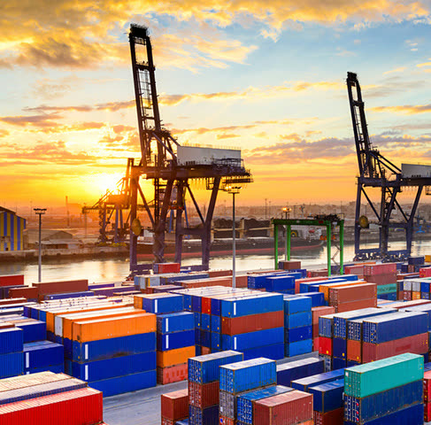 Container terminal at Gladstone — stacked shipping containers beneath gantry cranes at sunset.