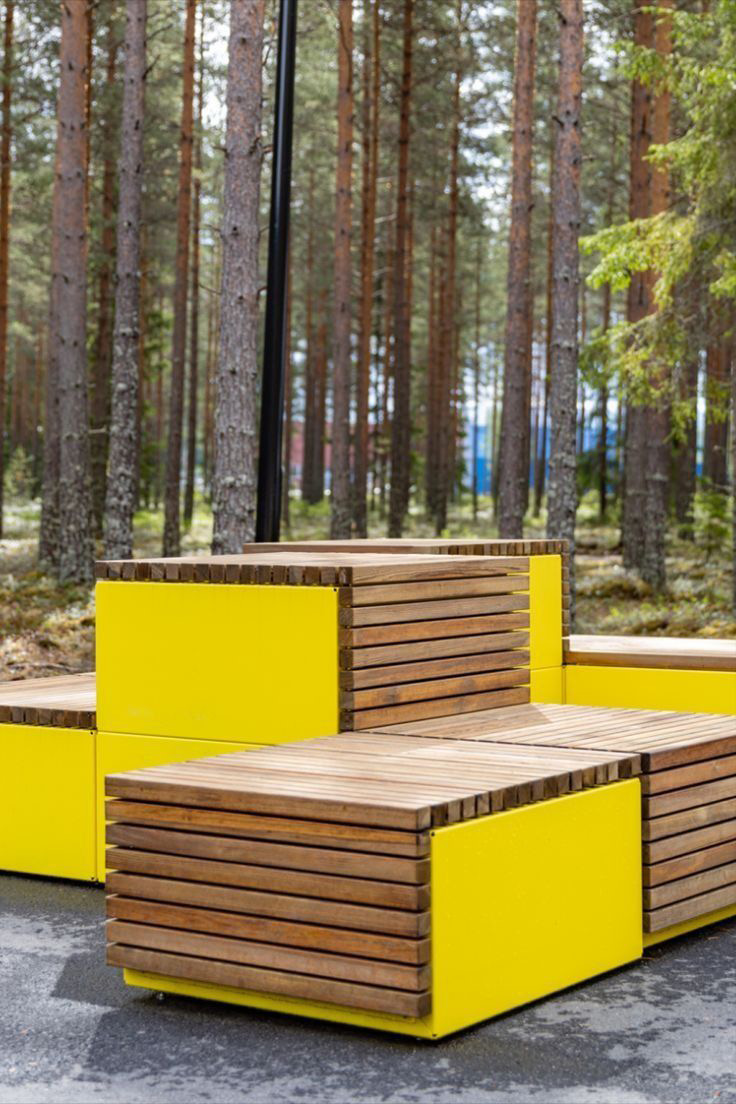 Reference image: stacked timber bench structures with bright side panels among trees.