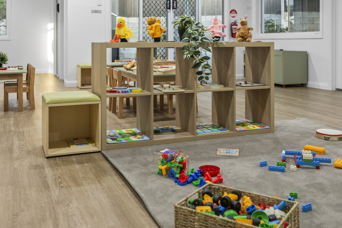 A light-filled First5Years Calliope room with timber tables, shelving and construction materials.