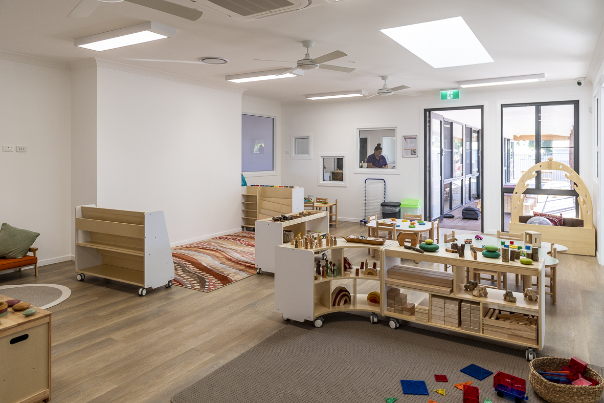 A wide view of a First5Years Emerald learning environment: timber shelving, low tables and natural light.