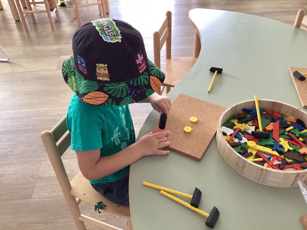 A child using a hammer and loose materials at First5Years Emerald.