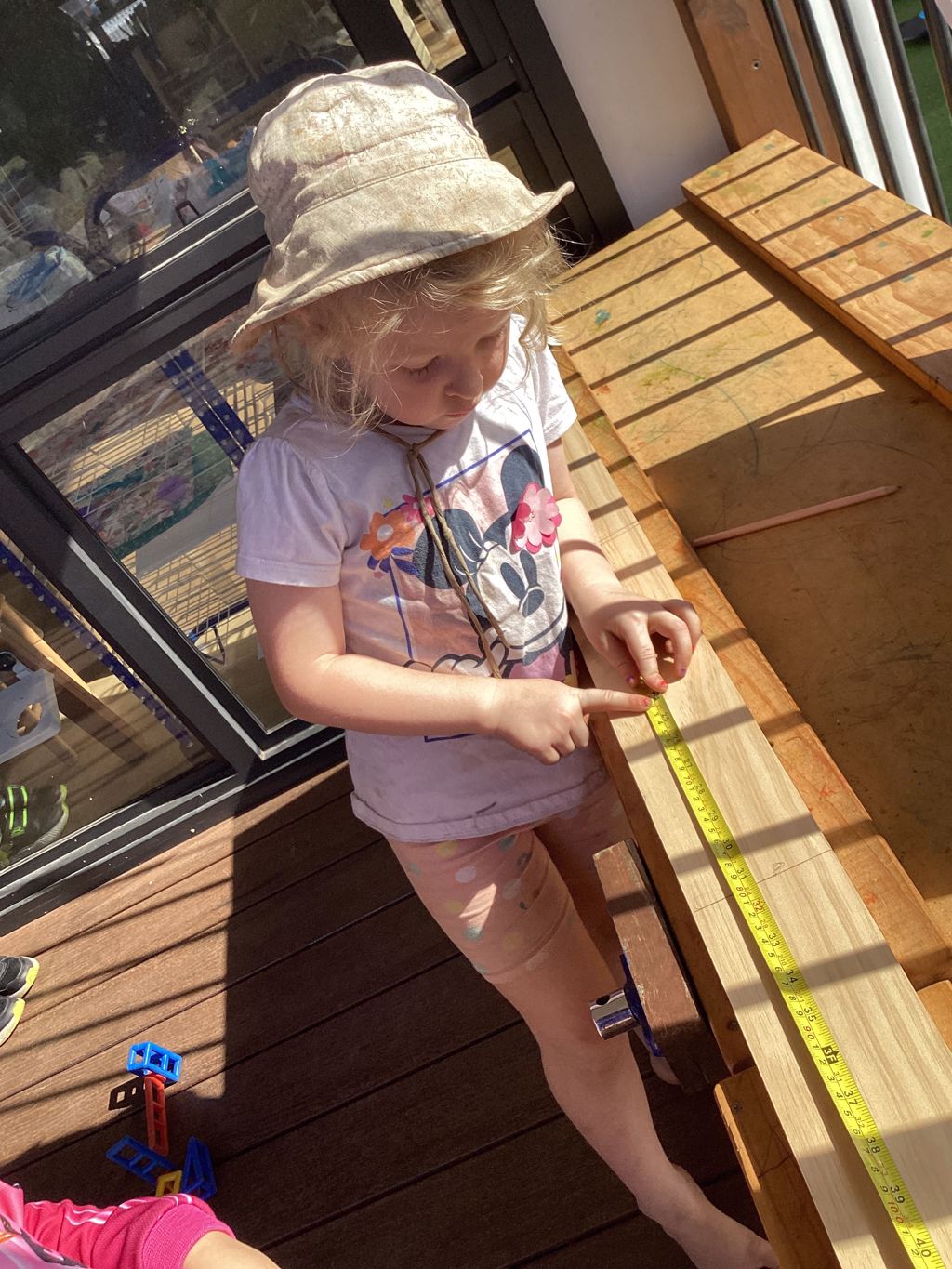 A child at First5Years Emerald measuring a length of timber, concentrating on the task.